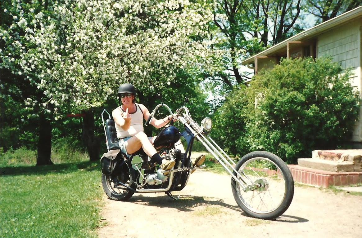 Larry posing on a chopper motorcycle wearing a bandana