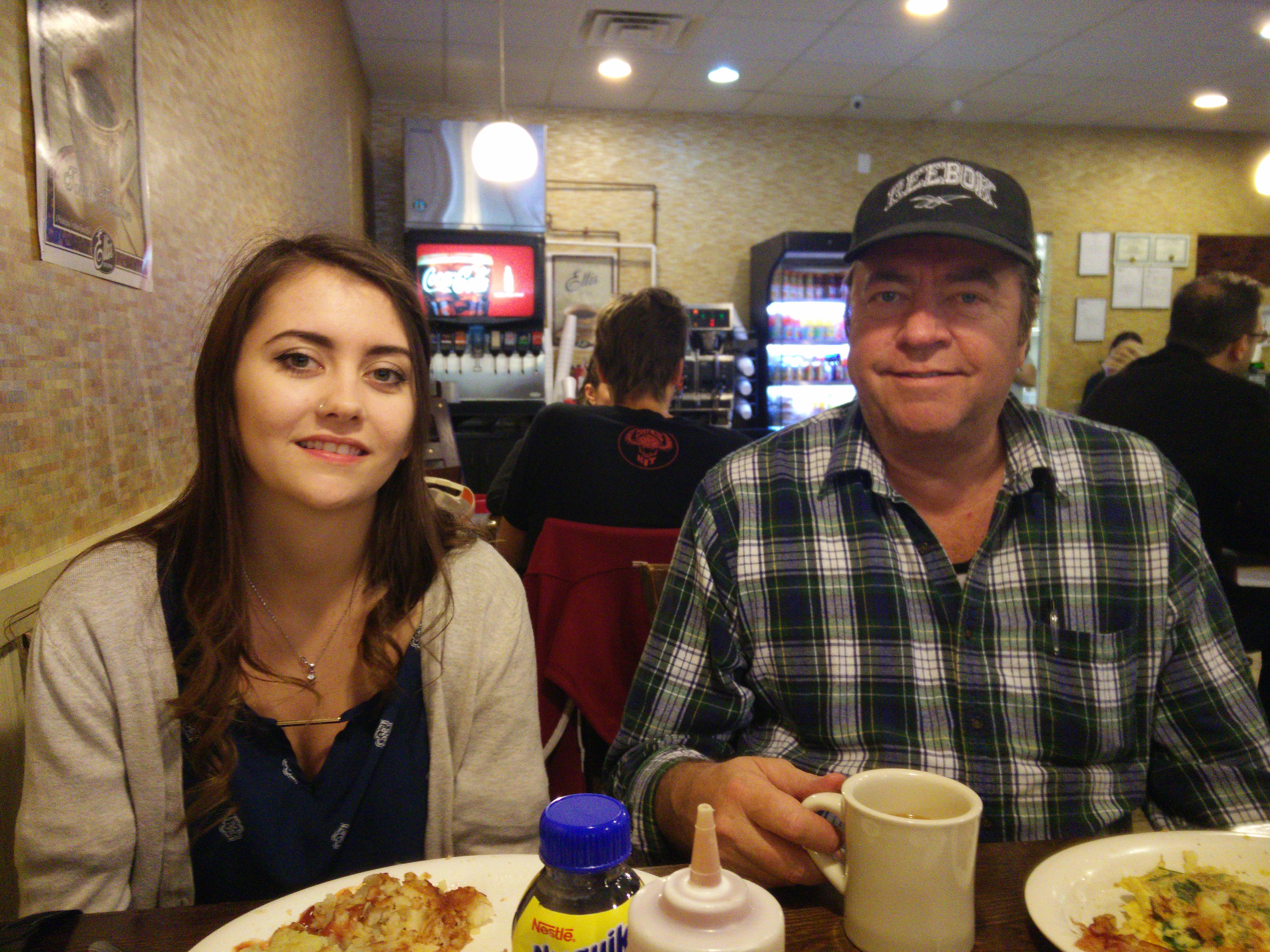 Larry in plaid shirt and Reebok cap at a diner with his daughter Kim, 2016