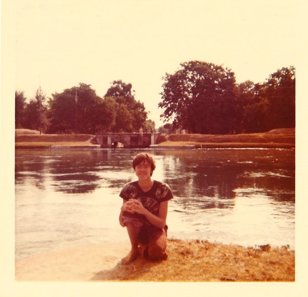 Larry kneeling at the edge of a river — a tributary of the Ganges — in India, 1972