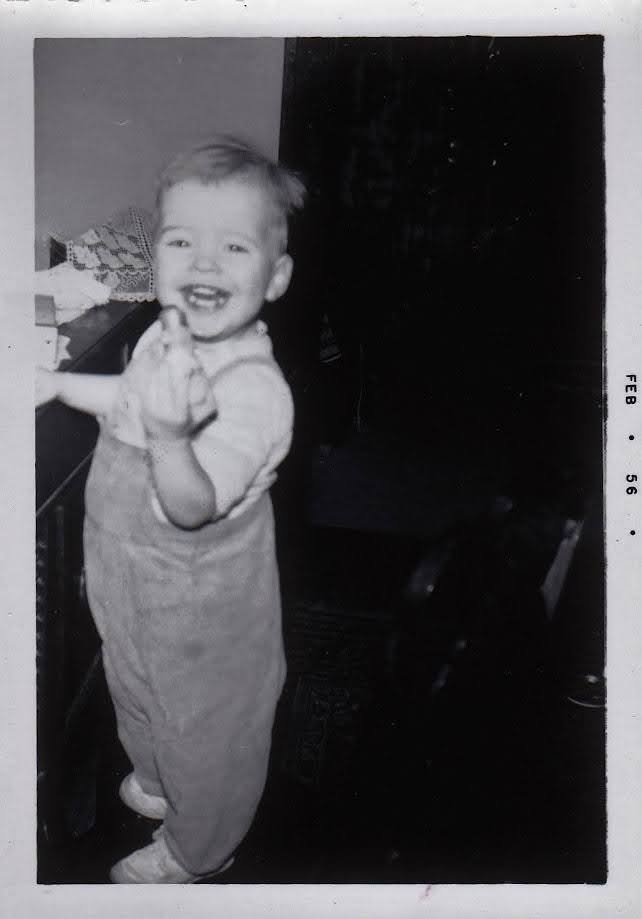 Larry as a smiling toddler in overalls