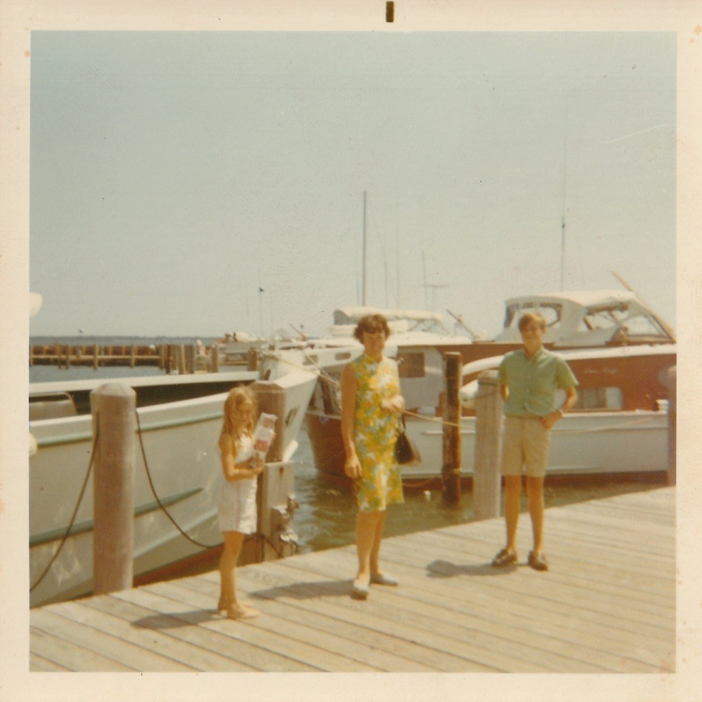 A family at a boat dock, woman in a floral dress with two kids