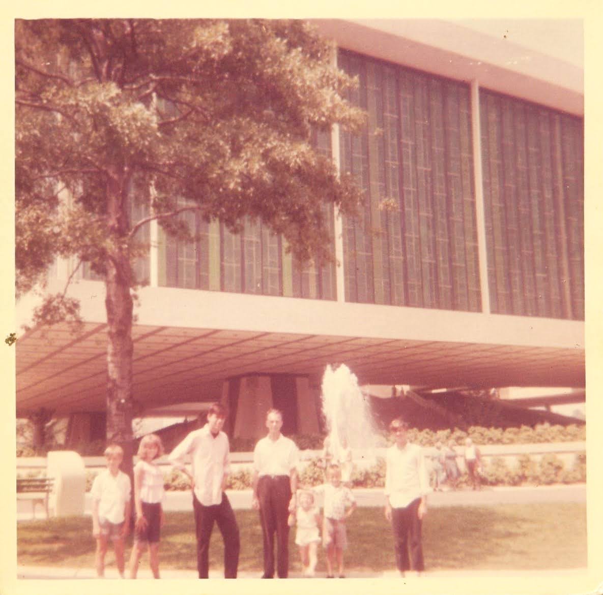 Family in front of a modern building with a fountain at the New York World's Fair