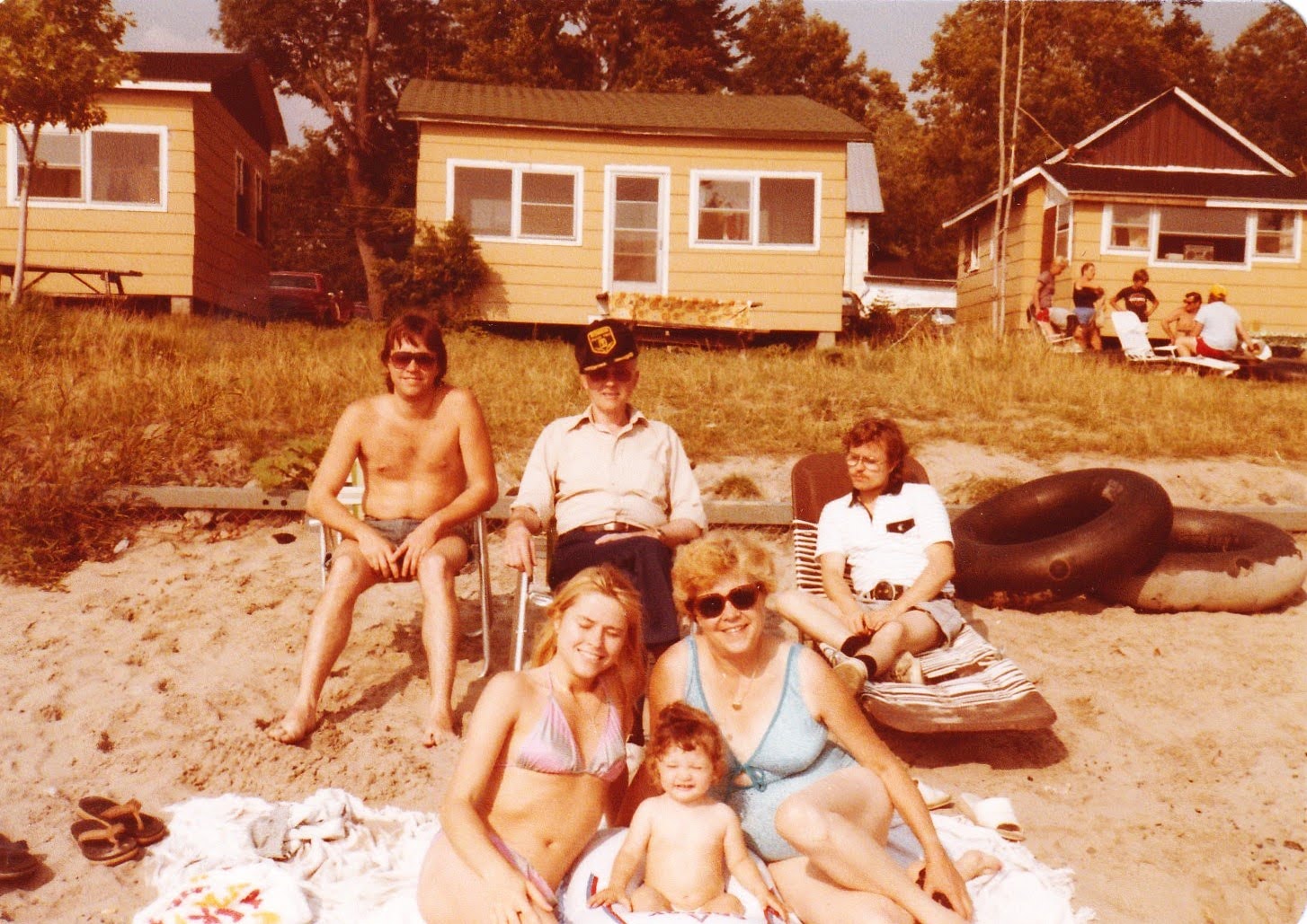 The family at Long Beach, Canada: Larry, Edwin in a captain's hat, Rosa, Jan in sunglasses, and others, with rental cabins behind
