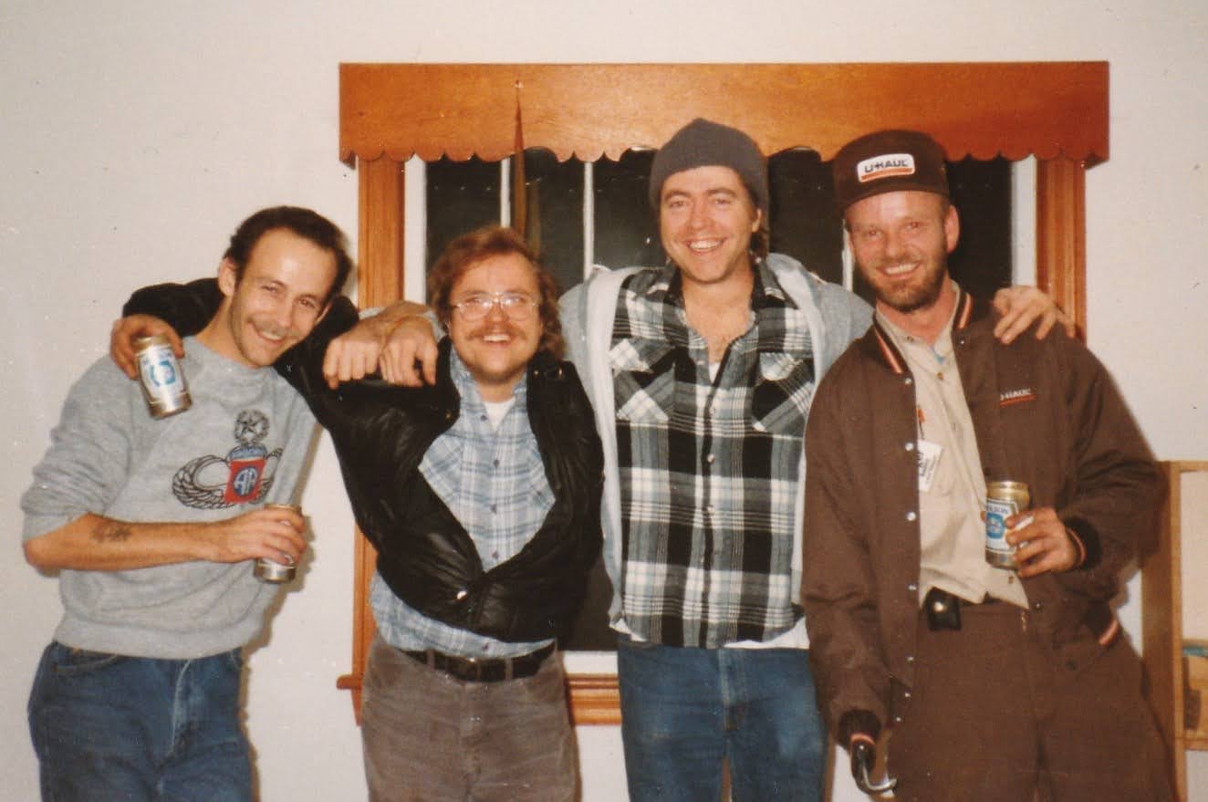 The four-man moving crew with beers, posed by a window: Roger, Rick Clark, Mark, and Larry